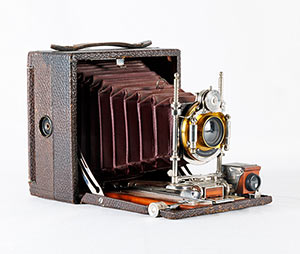 Colour image of a folding camera with metal and wood hardware, leather bellows and exterior