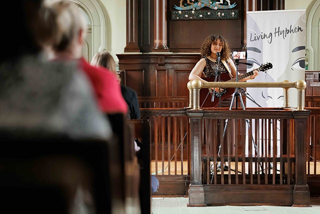 A woman playing a guitar in the PAMA courthouse