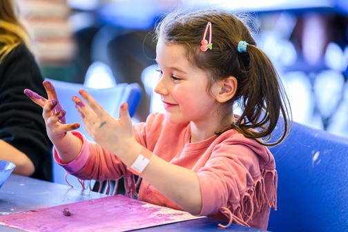 young girl doing arts and crafts with paint 