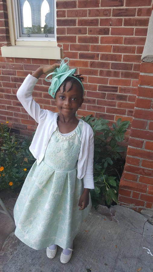 A young girl wearing a Church clothes and a hat