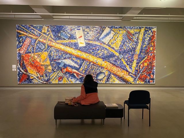 A person sitting on a bench looking at art